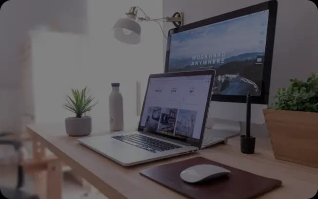 Laptop screen on a desk surrounded by green plants, showing a clean, modern workspace with natural elements.