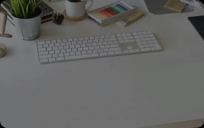 Simple desk with a clean keyboard and small potted plants, creating a minimalist and refreshing workspace.